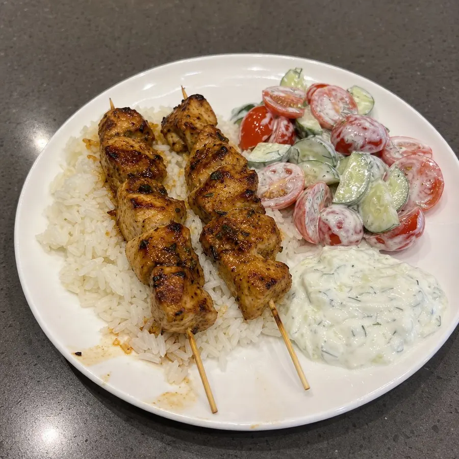 Brochettes de poulet BBQ au four, riz et salade de tomates et concombres au tzatziki